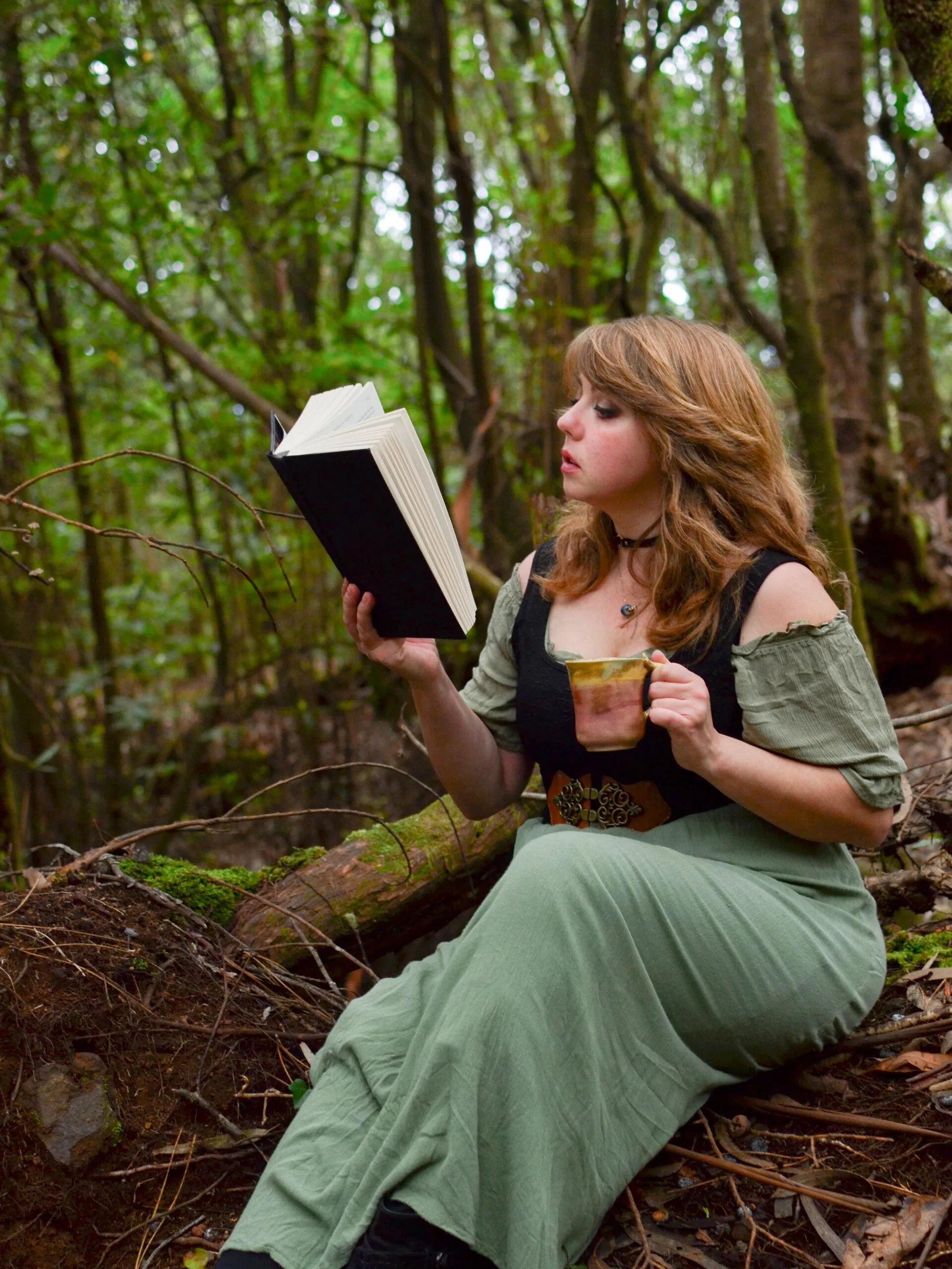 Anna in the Madeira forest holding a handmade ceramic mug