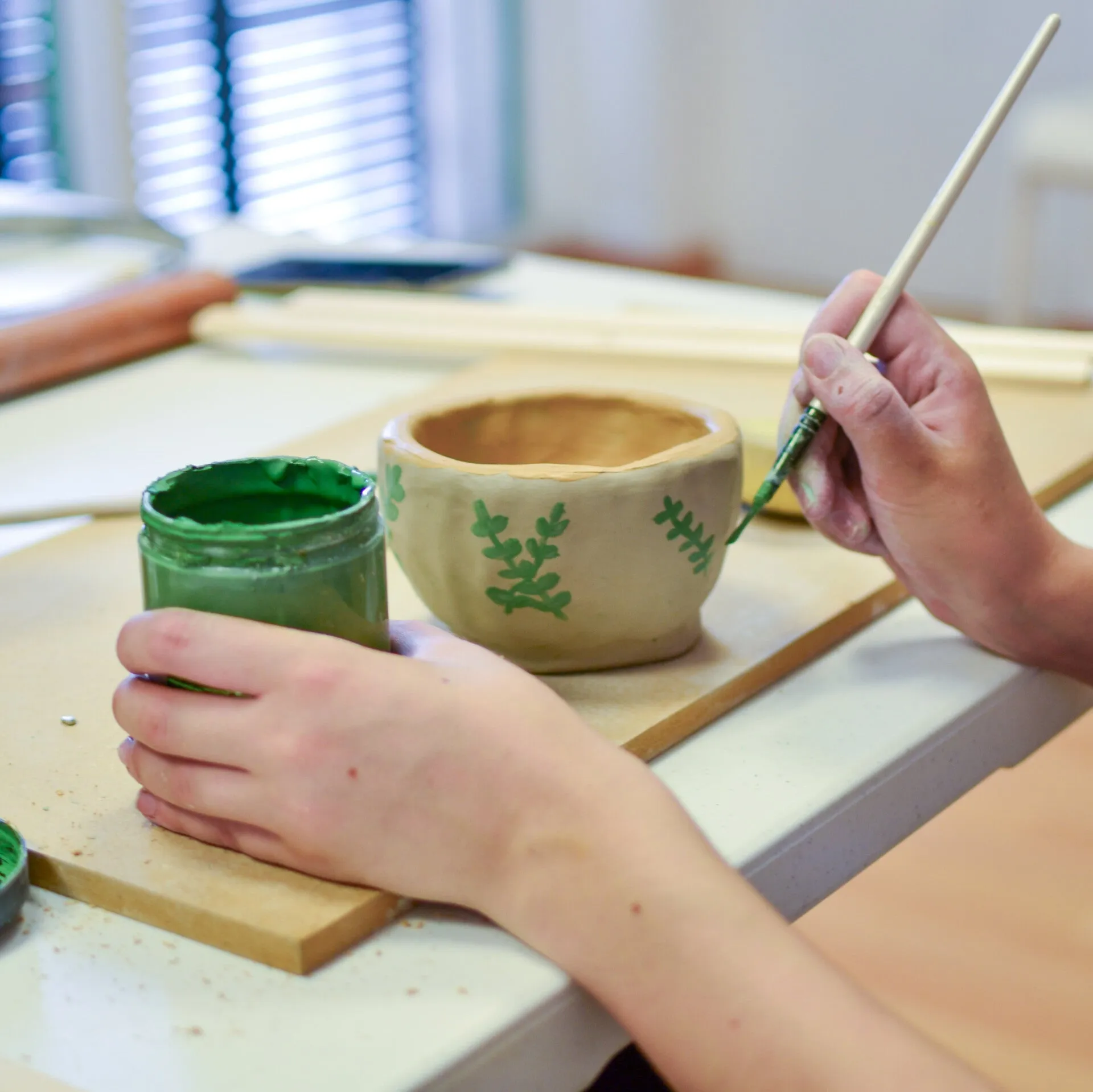 Hands hand-painting a ceramic bowl in the studio