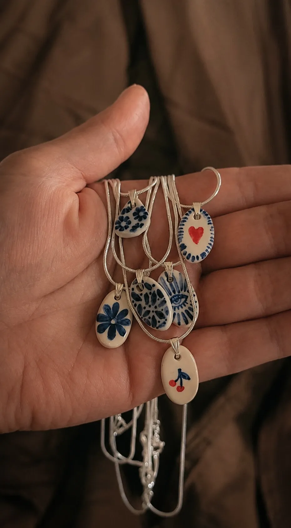 Hand-painted ceramic pendants held in a hand
